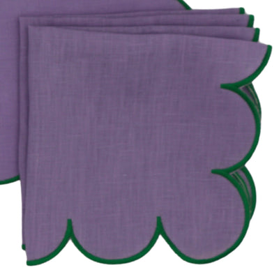 Set of four lilac linen napkins with green embroidered edges folded neatly on a white surface