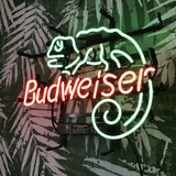 Neon light sign with a green lizard outline curling its tail above red 'Budweiser' text, mounted on a dark green wall with white fern leaf patterns.