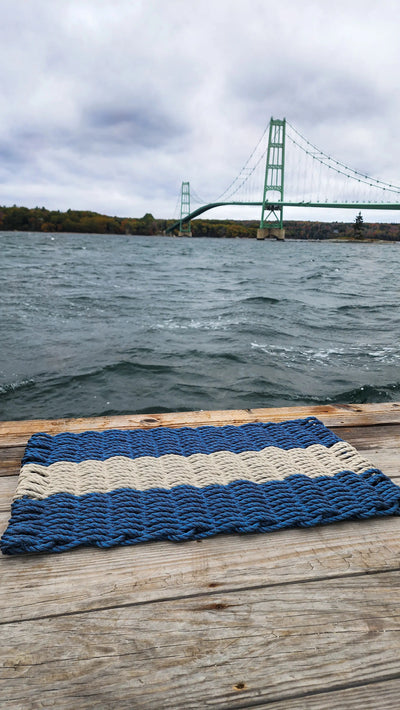 Handmade navy blue and tan lobster rope mat on wooden floor