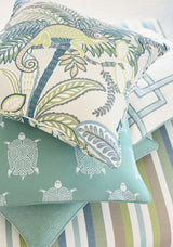 Stack of decorative pillows featuring a tropical chameleon pattern atop white and blue turtle motifs with striped fabric underneath in soft greens and blues.