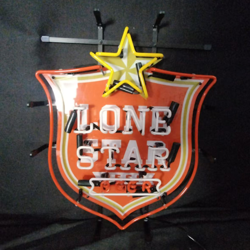 Neon sign shaped like a red shield with a yellow star on top and the words 'LONE STAR BEER' in white neon letters inside.