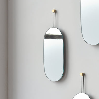 Soft-oval shaped Lure Mirror - Single hanging on a white wall reflecting neutral-toned interior