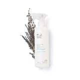 Bottles of MORE® Stainless Steel Cleaner & Polish in Lavender Verbena and Peppermint-Thyme scents with microfiber cloth on dark wood