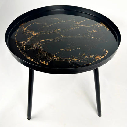 Round black small resin table with gold marble pattern on a white background