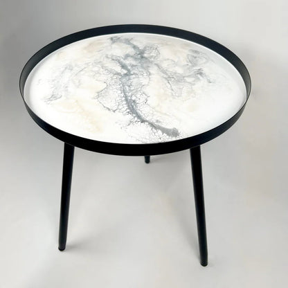 Round resin table with marble-like top and black frame on a white background