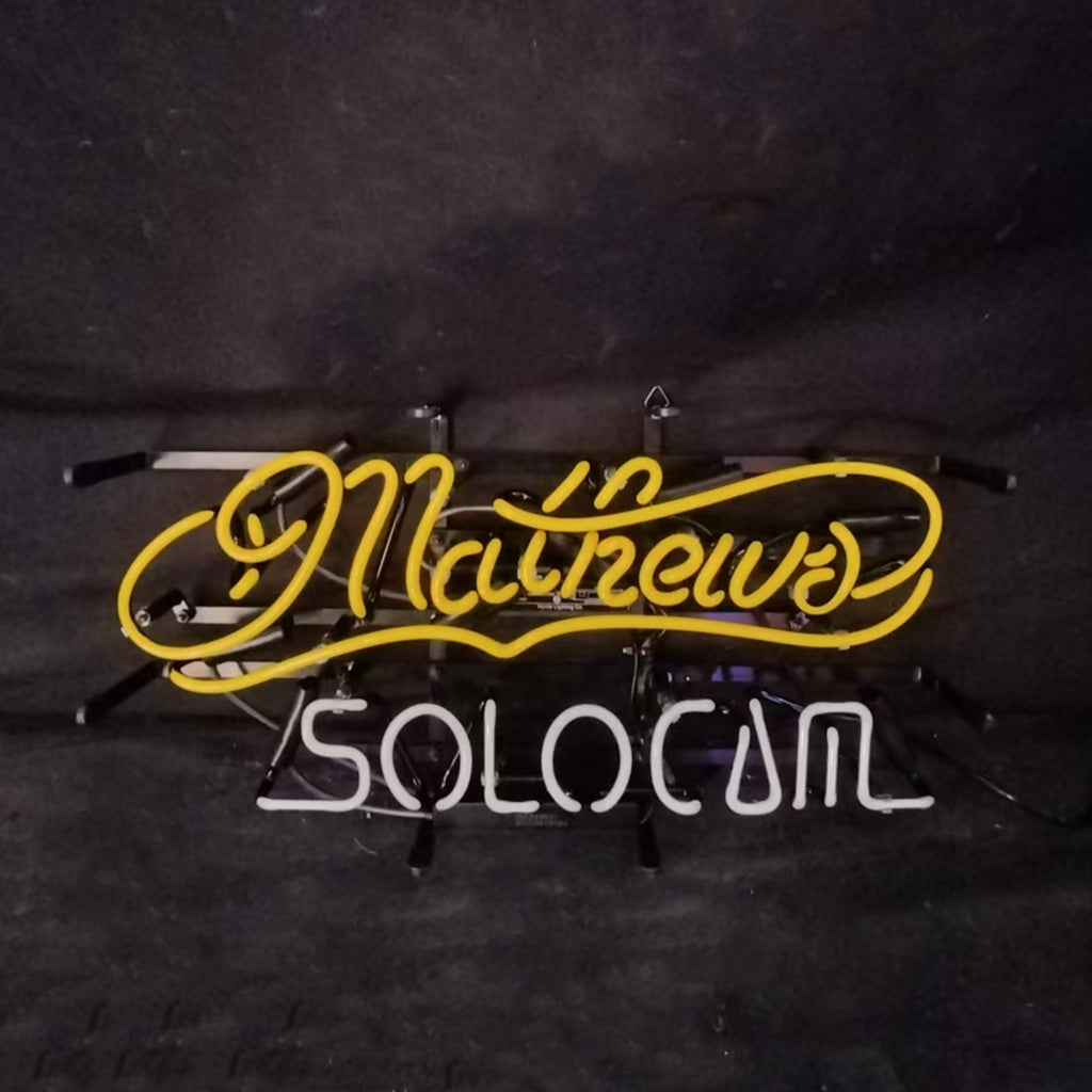Yellow cursive neon sign reading 'Mathews' above white block letters spelling 'SOLOCUM' against a dark background.