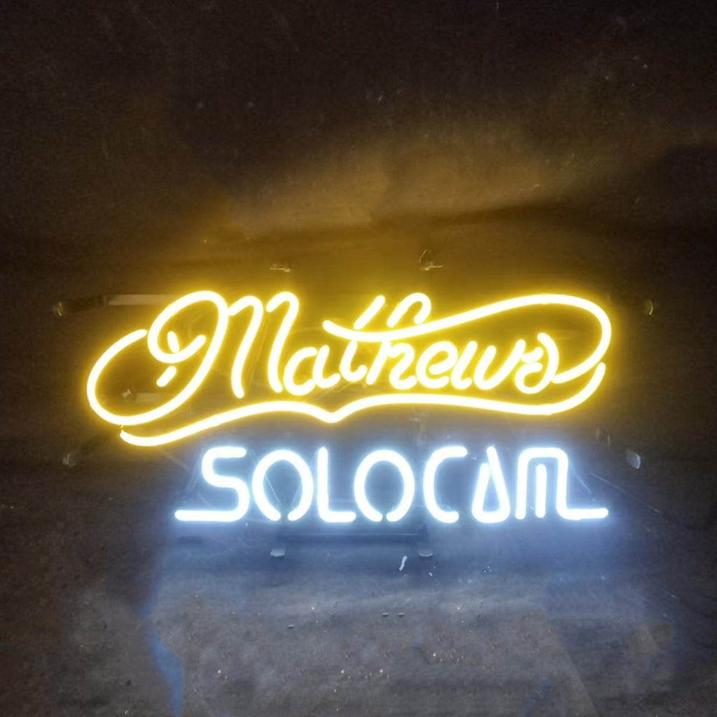 Mathews Solocom Neon Sign illuminated on a metal grid, showcasing glowing blue and purple tones