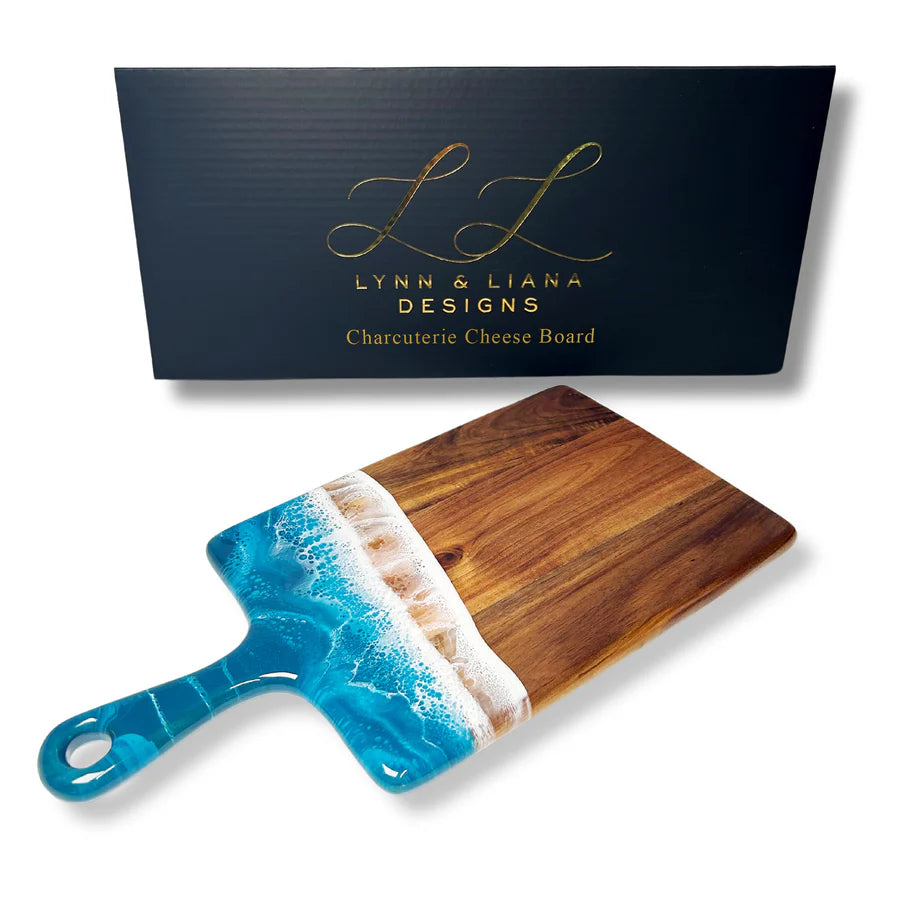 Wooden resin charcuterie board with blue handle resembling ocean waves, branded 'Lynn & Liana Designs'.