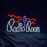 Neon sign with red lightning bolts above a blue and white microphone graphic, spelling out 'Radio Room' in white neon letters against a dark background.