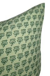 Close-up of a green pillow cover patterned with small, repeating dark green stylized floral motifs arranged in neat rows on a muted green background.