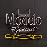 White and yellow neon sign reading 'Modelo Especial' with script and block lettering on a black background, mounted on a black metal frame with power unit.