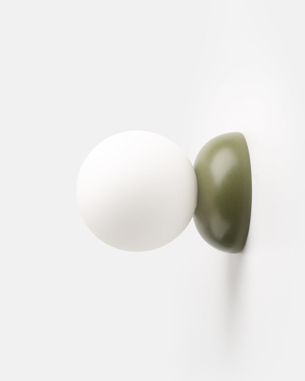 Monroe Sconce in Moss glaze mounted on wall emitting warm light