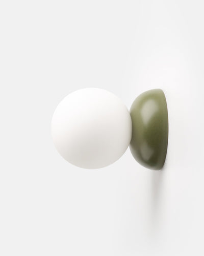 Monroe Sconce in Moss glaze mounted on wall emitting warm light