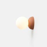Spherical white glass globe light fixture mounted on a half-sphere rust-colored wall base against a plain white background.