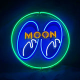 Circular neon sign with bright green outer ring, blue inner shapes resembling stylized eyes, white highlights, and yellow-orange uppercase text reading MOON.