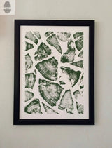 Black-framed print featuring green wood slice patterns arranged in a scattered collage on a white background, showcasing natural rings and textures.