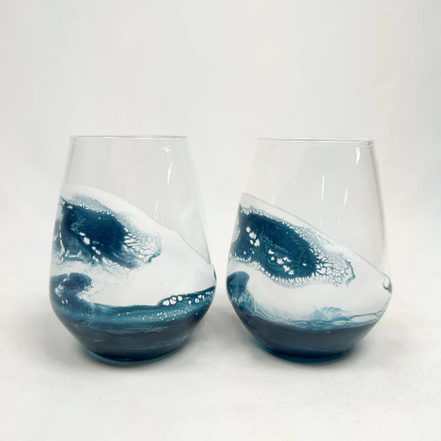 Two stemless resin wine glasses with blue and white wave design on a white background