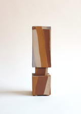 Tall square ceramic vase with a smaller square base, featuring bold vertical stripes in tan, brown, and off-white against a plain white background.