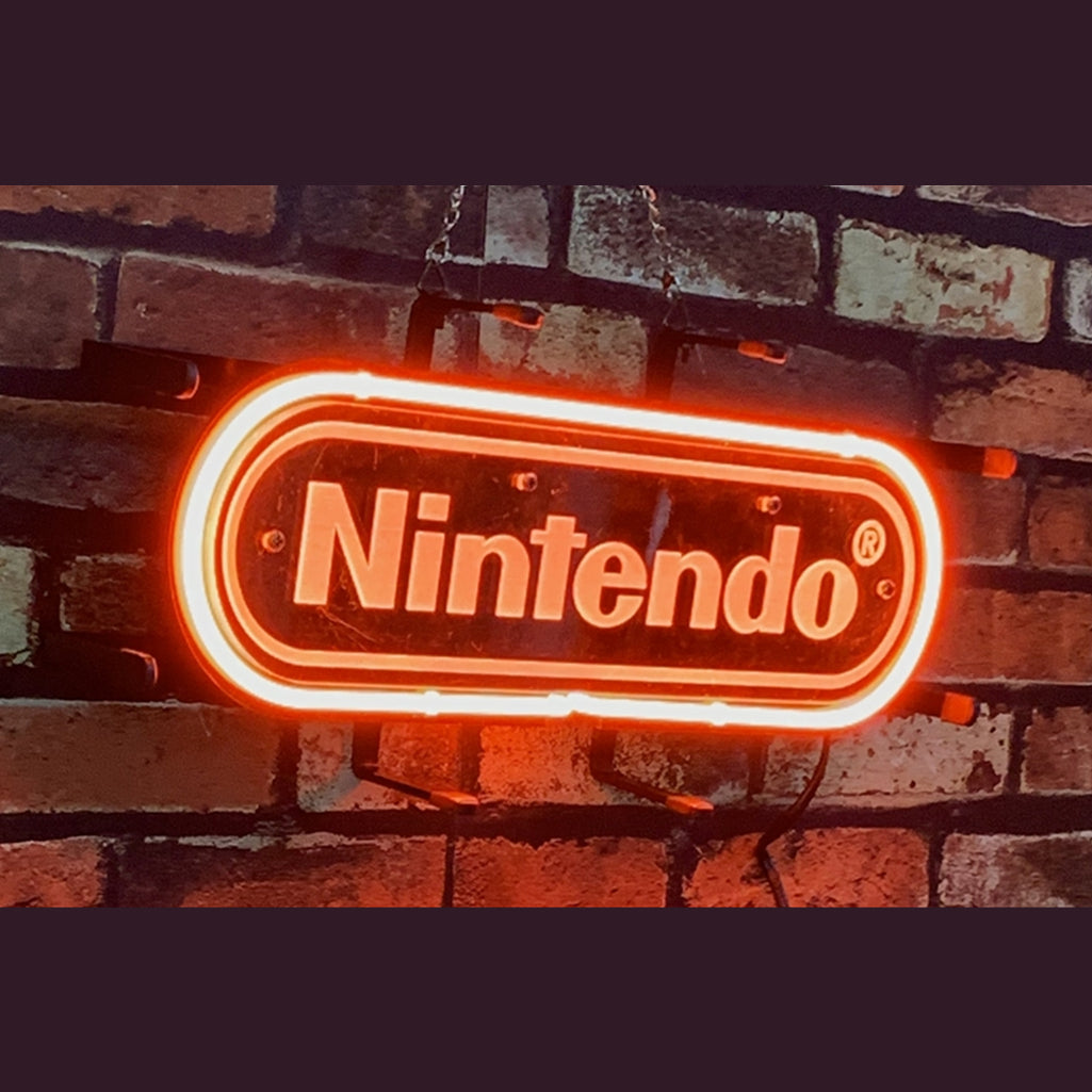 Red-orange neon sign displaying the word 'Nintendo' in a rounded rectangular shape against a dark brick wall background.