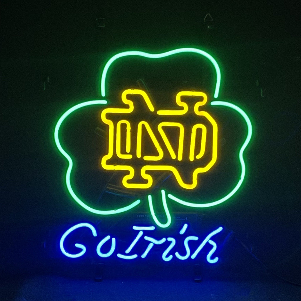 Neon sign featuring a green shamrock outline with yellow interlocking ND letters inside and blue cursive "Go Irish" text below on a black background.