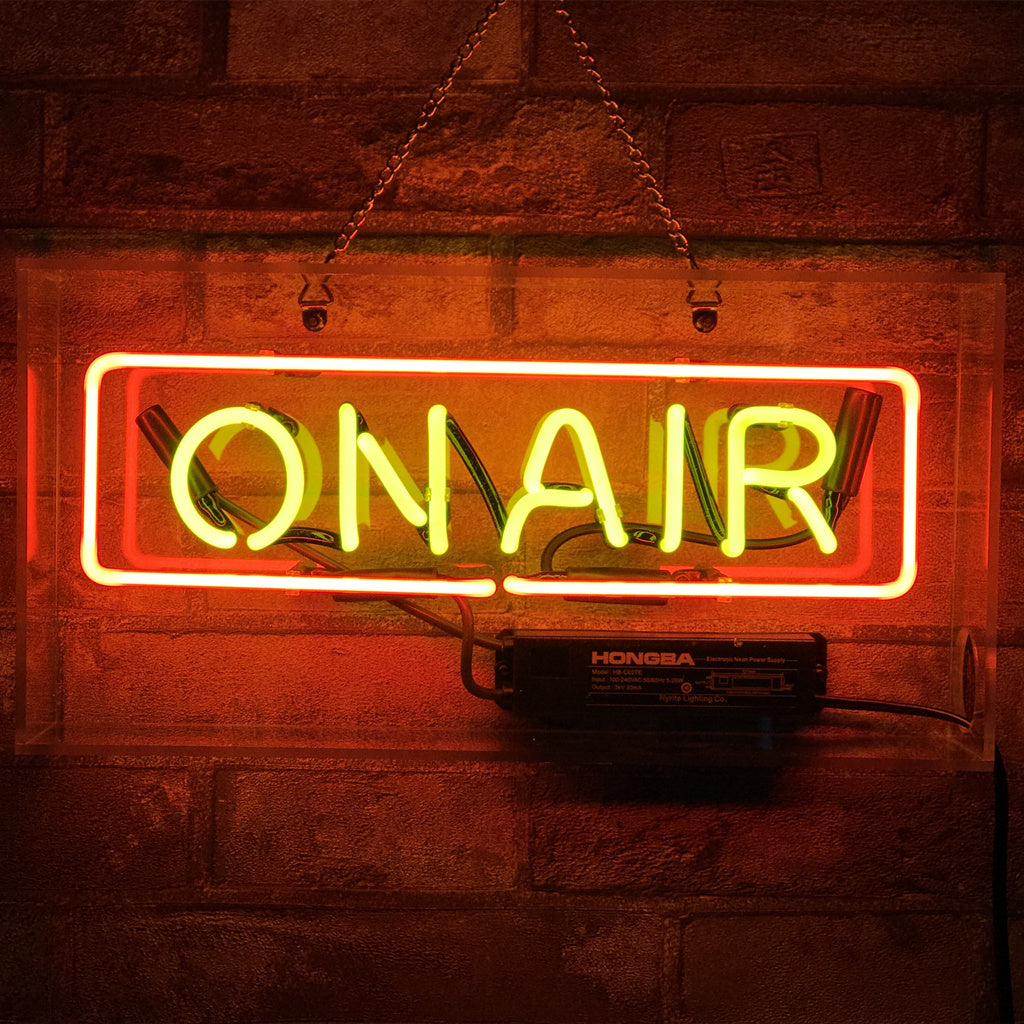 On Air Studio Neon Sign glowing in indoor space with metal chain hanging on acrylic backing