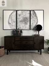 Triptych black and white woodcut prints depicting detailed tree rings, mounted above a dark wooden sideboard with drawers and cabinets, flanked by vintage decor.