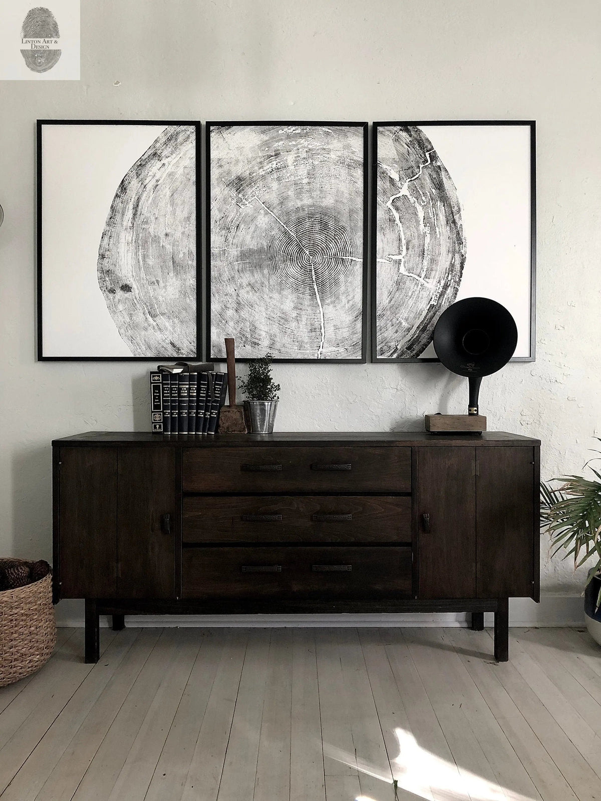 Triptych black and white woodcut prints depicting detailed tree rings, mounted above a dark wooden sideboard with drawers and cabinets, flanked by vintage decor.