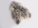 Irregularly shaped soft Icelandic sheepskin rug with long, fluffy fur in shades of grey and white on a light background.