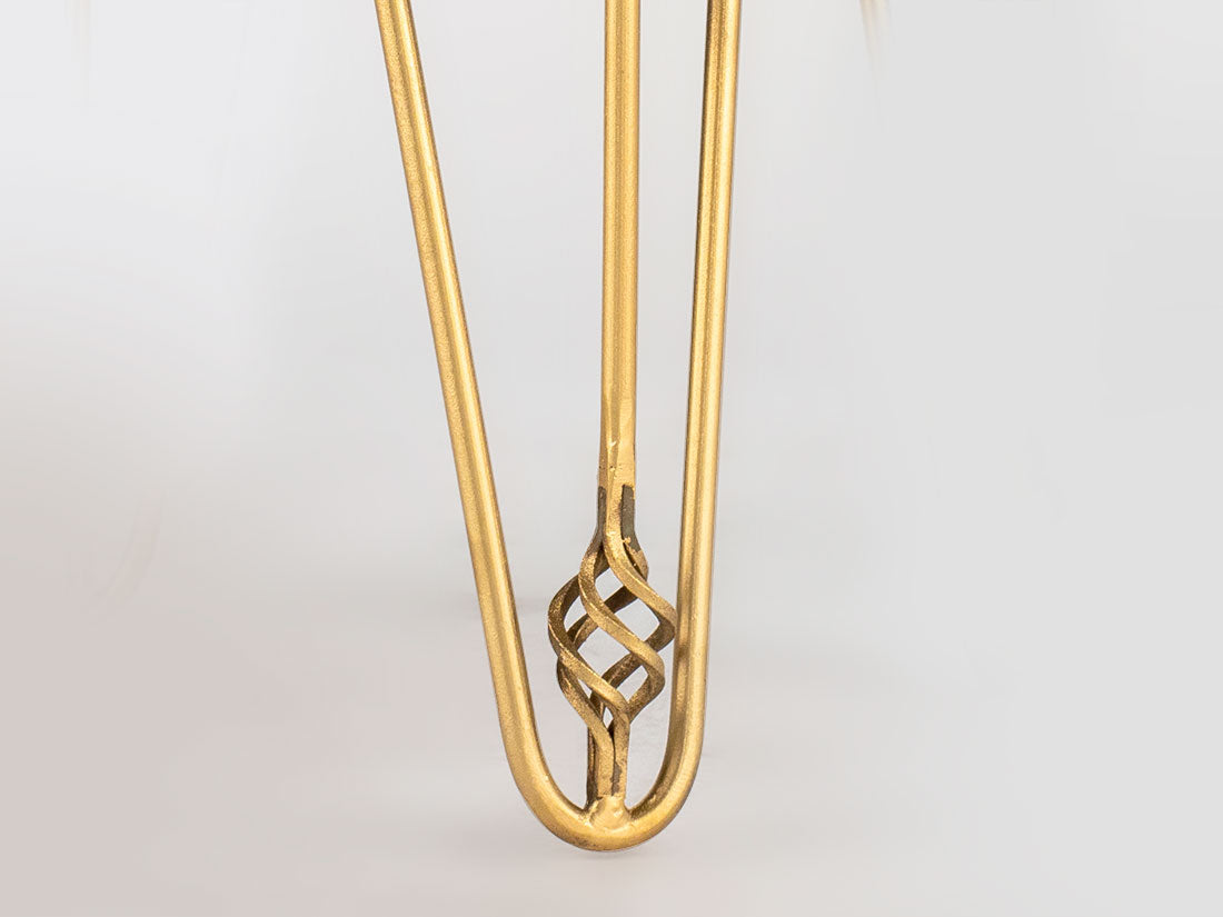 Close-up of a brass hairpin leg featuring a decorative twisted knot near its bent end against a plain white background.