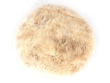 Round beige sheepskin pouf with soft, fluffy texture and natural curly wool pattern, shown from above on a white background.