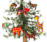 Seven colorful zebra ornaments with geometric and striped patterns hanging on a small pine tree against a white background.