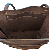 Interior of a dark brown leather tote bag showing a large inner pocket with brass rivets and textured suede lining.