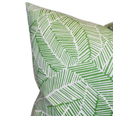 Close-up of pillow with abstract leaf pattern in varying shades of green on white background, featuring linear, broken stripe textures.