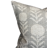 Close-up of a sand grey pillow cover with a subtle white floral pattern of stylized zinnia flowers and leaves on textured fabric
