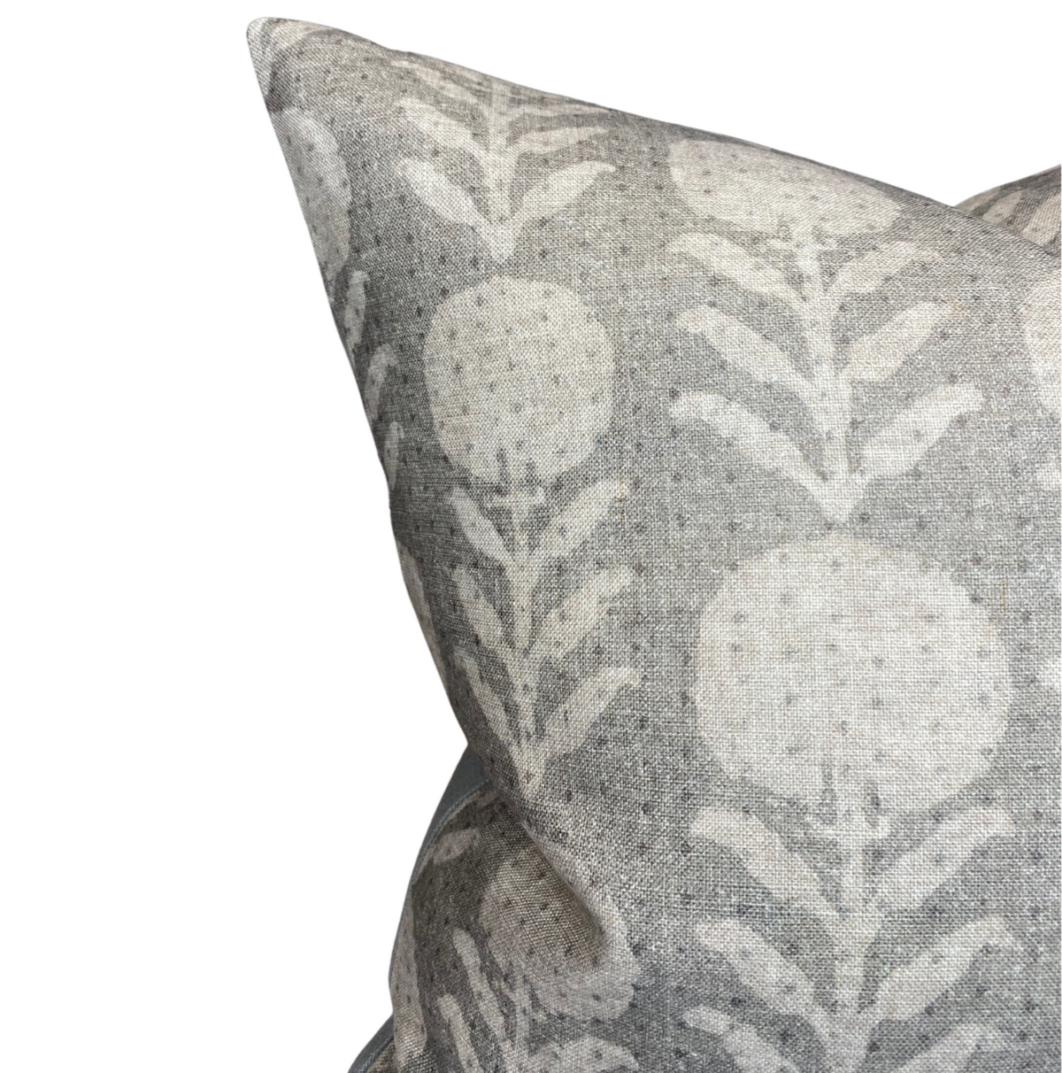 Close-up of a sand grey pillow cover with a subtle white floral pattern of stylized zinnia flowers and leaves on textured fabric