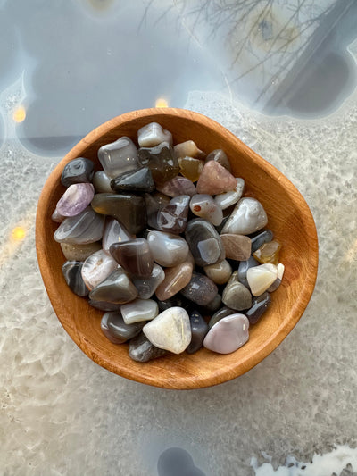 Collection of colorful assorted tumbled natural stones with polished surfaces arranged on a flat surface