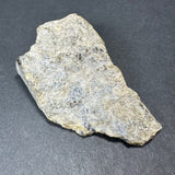 Irregularly shaped labradorite rough stone with a shimmering silvery-gray surface and subtle iridescent flashes, resting on a dark gray background.