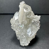 Clear apophyllite crystals with white stilbite clusters on a chalcedony base, displayed against a dark background highlighting their translucent, prismatic forms.