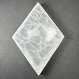 Diamond-shaped small selenite slice with white translucent crystalline texture on dark gray background