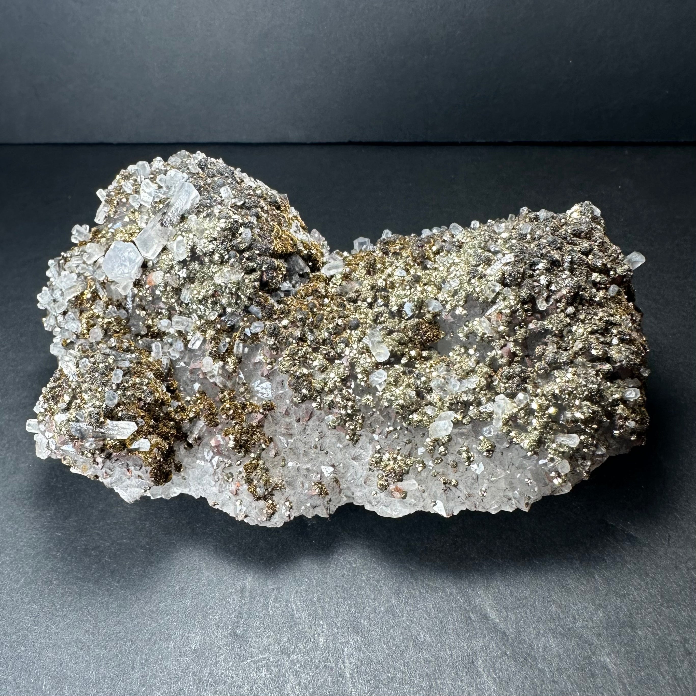 Marcasite crystals on colorless Calcite mineral from Morocco displayed on a dark background