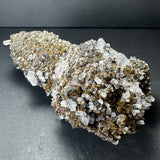 Cluster of dark brown marcasite crystals densely covering translucent, colorless calcite crystals on a roughly conical mineral specimen against a dark background.