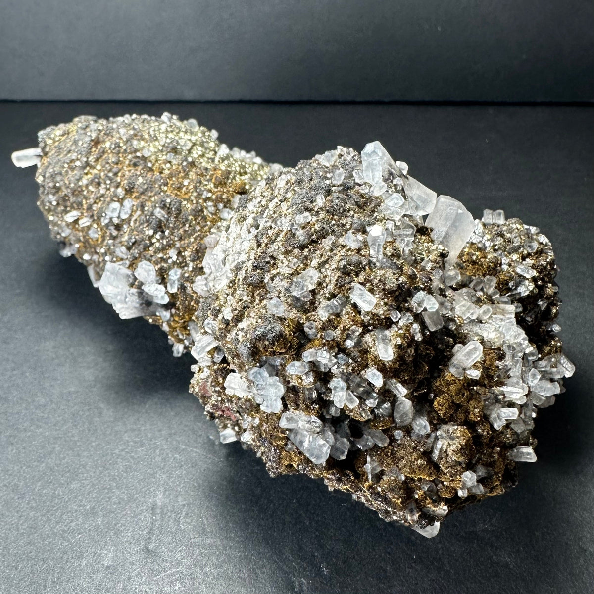 Cluster of dark brown marcasite crystals densely covering translucent, colorless calcite crystals on a roughly conical mineral specimen against a dark background.