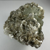 Cluster of translucent aquamarine crystals intergrown with silvery muscovite flakes and pale albite, showing layered, reflective surfaces and angular shapes.
