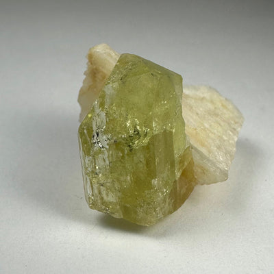 Close-up photograph of Brazilianite with Albite mineral specimen showing pale yellow Brazilianite crystals on white Albite matrix