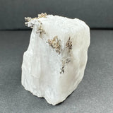 Rough white calcite crystal displaying delicate branching native dendritic silver formations on its edges, set against a dark gray background.