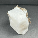 Translucent white calcite with metallic dendritic silver formations concentrated along the top edge against a dark gray background.