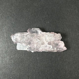 Translucent pale pink rose quartz crystal cluster with layered, jagged formations, displayed on a dark gray textured background.