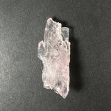 Translucent pale pink rose quartz crystal cluster with irregular prismatic formations on a dark textured background.