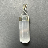 Clear selenite crystal pendant with smooth, translucent surfaces set in a polished sterling silver clasp against a textured gray background.