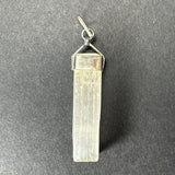Rectangular translucent selenite crystal pendant with vertical striations, set in a shiny sterling silver clasp and loop on a dark textured background.